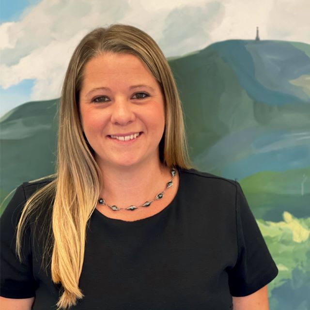 Cassie Rochelo, wearing a necklace and smiling with a mural of mount greylock in the back