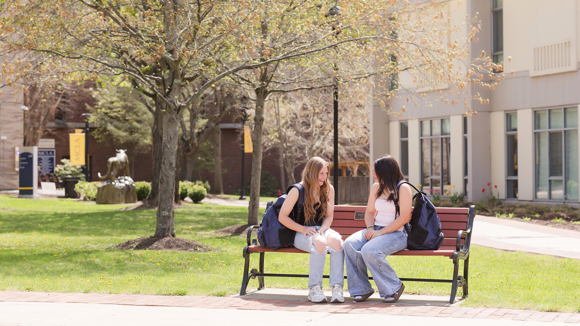 MCLA campus with two students sitting on a bench